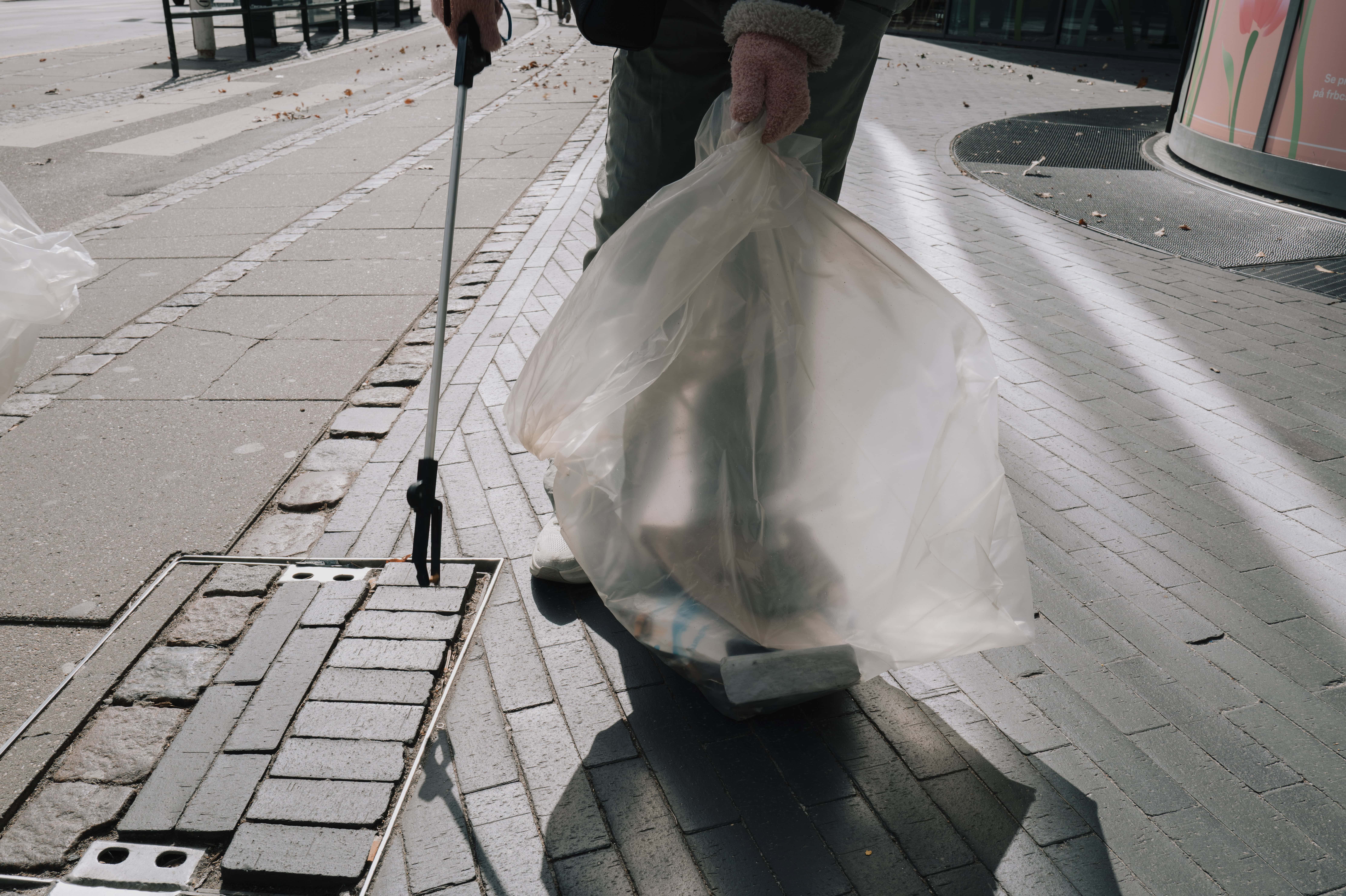 Medarbejder fra StreetPeople med skraldepose under arbejde i København
